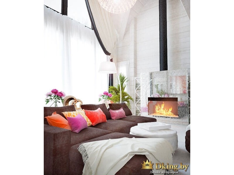 шоколадный диван с яркими подушками на фоне белых стен и текстиля. в углу камин